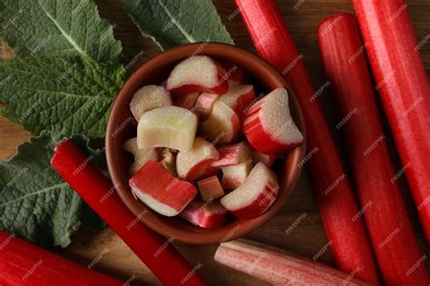 Stalks of fresh rhubarb with leaves and a bowl of rhubarb, chopped, in a bowl.