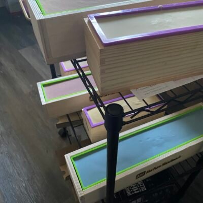 Loaves of soap in the molds on a large rolling rack waiting to be cut into bars.